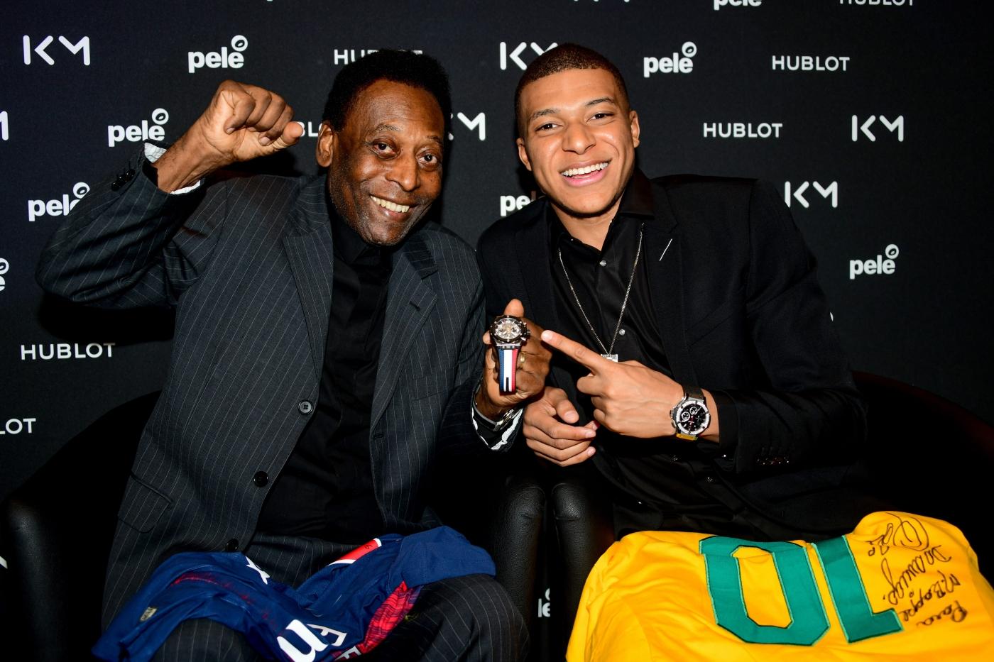 Pelé and Kylian Mbappé holding Hublot watches